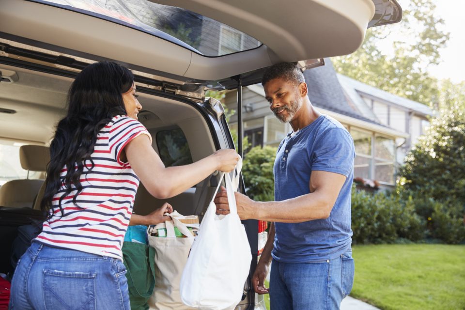 Couple organizing groceries in their car's trunk.