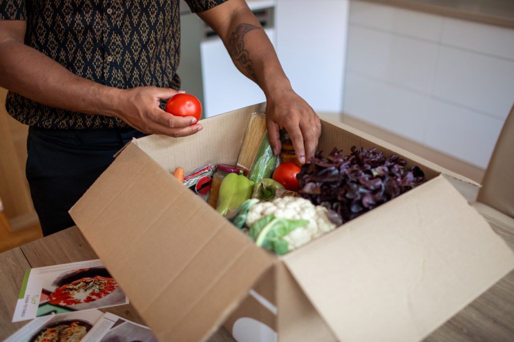 Man opening parcel with meal kit.