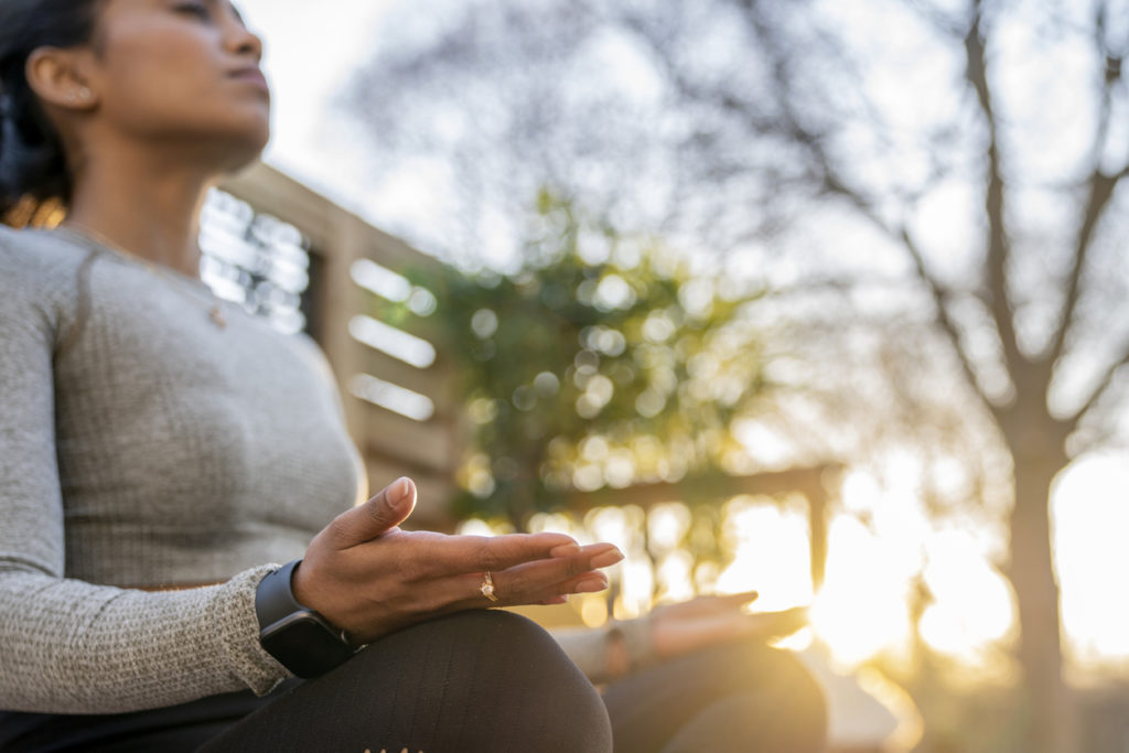 Female doing relaxing yoga in her backyard while the sun sets behind her.