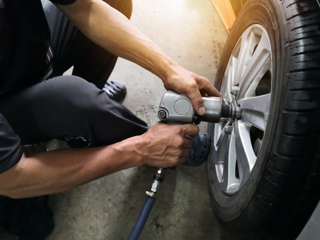 Car mechanic removing tire from car