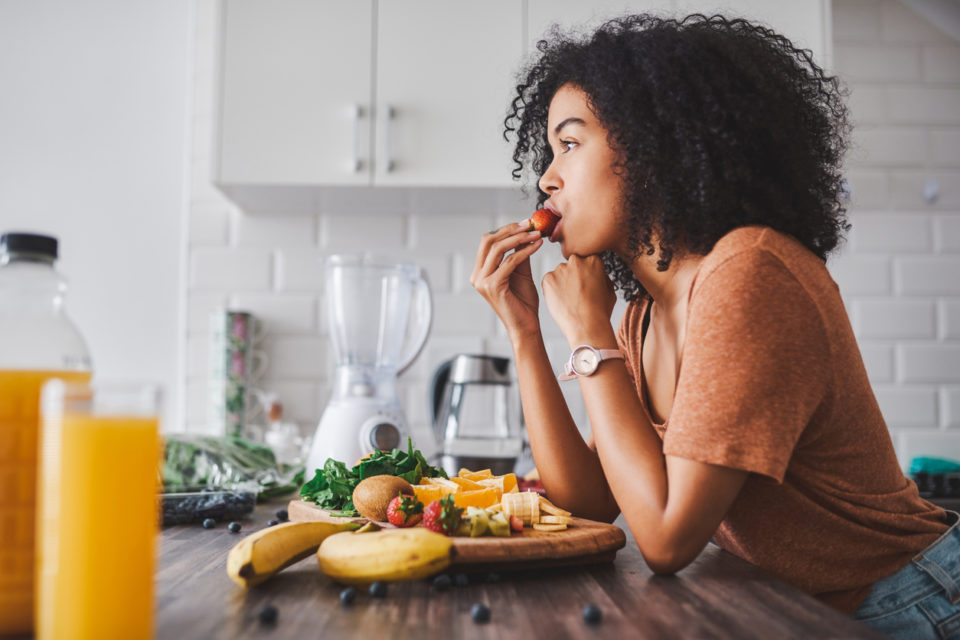 Shot of a young woman making a snack with fruit at home