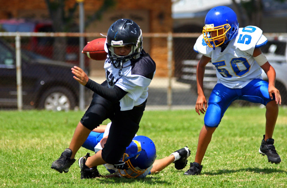 Young american football player running back breaking away from an attempted tackle.