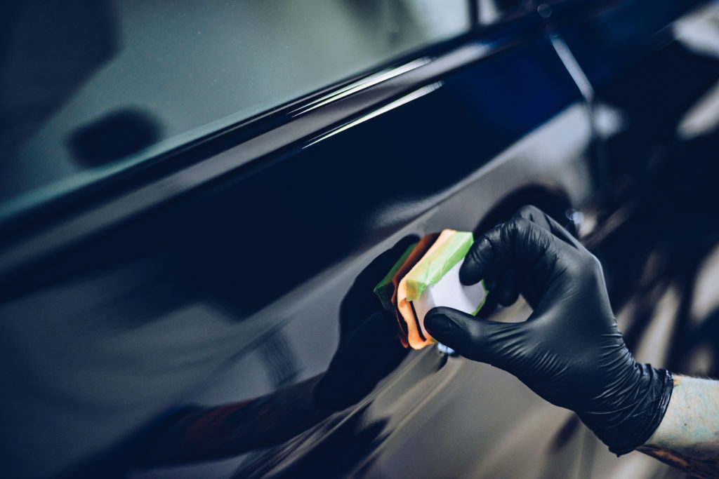 Man worker in car wash polishing car.