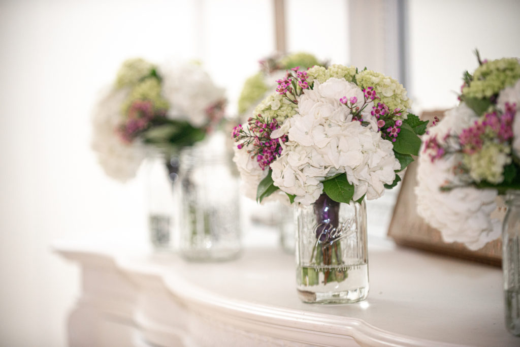 White hydrangea bridal bouquets in mason jars on white dresser with mirror
