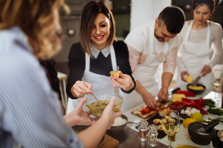 Photo of a young woman in a kitchen during a cooking class, preparing bruschetta