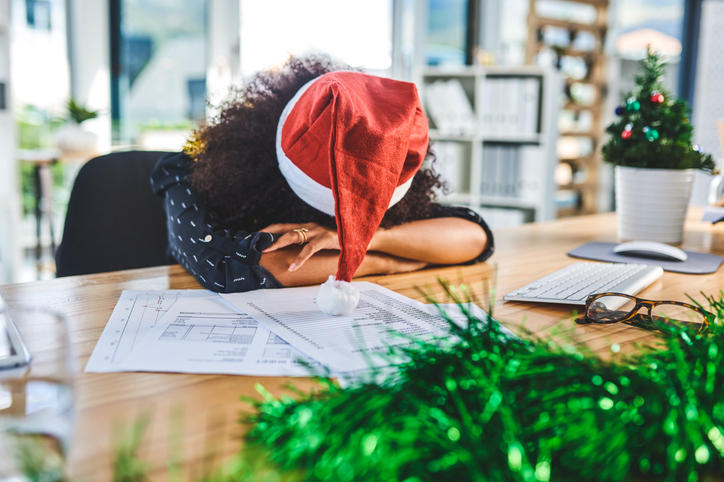 Cropped shot of an attractive young businesswoman wearing a Christmas hat laying her head down on the desk