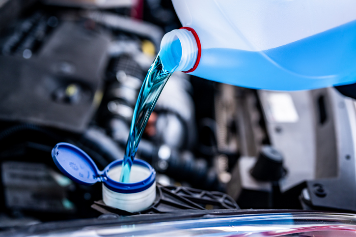 Pouring antifreeze. Filling a windshield washer tank with an antifreeze in winter cold weather.